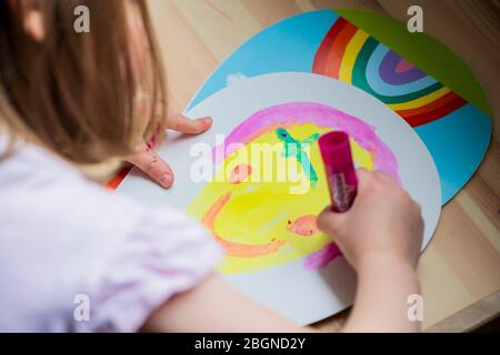 Ein junges Mädchen malt ein Smiley Gesicht während der Heimschulung Stockfoto