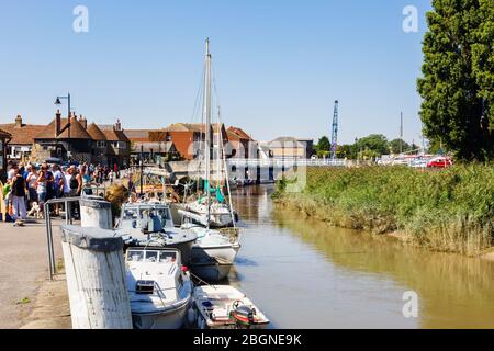 Boote auf dem Fluss Stour am Quay mit Menschen in der historischen Cinque Port Stadt Sandwich, Kent, England, Großbritannien beschäftigt Stockfoto