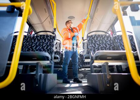 Berlin, Deutschland. April 2020. Ein Mitarbeiter reinigt den Passagierbereich eines BVG-Busses an der Haltestelle Kurt-Schumacher-Platz. Teams von zwei bis drei Mitarbeitern reinigen täglich bis zu 20 Busse, um das Coronavirus zu enthalten. Seifenlauge werden als Reinigungsmittel verwendet. Kredit: Kay Nietfeld/dpa/Alamy Live News Stockfoto