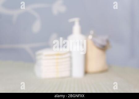 Verschwommener Hintergrund mit neugeborenen Babypflegeprodukten. Lotion, Pulver und Windeln auf Wickeltisch im Kinderzimmer. Weiche blaue und grüne Jungen Farben. Stockfoto