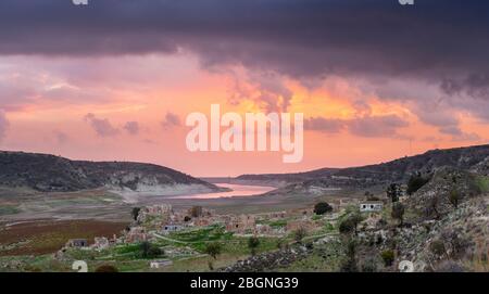 Panoramablick auf einen dramatischen Sonnenuntergang über den Ruinen des verlassenen Dorfes Foinikas, Paphos District, Zypern Stockfoto