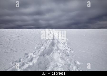 Fußabdrücke auf dem Schnee gegen dunkle bewölkten Himmel Hintergrund Stockfoto