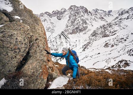 Touristische mit Dreadlocks klettert den Rock in Snowy Mountains Hintergrund Stockfoto