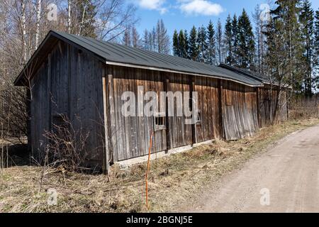 Baufälliges und verwittertes Bauernhaus an Schotterstraße in Tuusula, Finnland Stockfoto