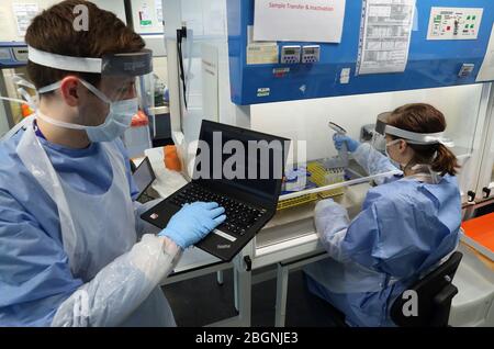 Techniker führen während der Eröffnung des neuen Covid-19-Testlabors am Queen Elizabeth University Hospital in Glasgow einen Probentransfer durch. Stockfoto