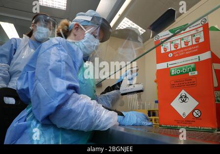 Techniker führen während der Eröffnung des neuen Covid-19-Testlabors am Queen Elizabeth University Hospital in Glasgow einen Probentransfer durch. Stockfoto