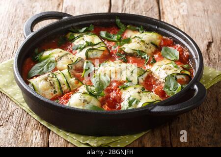 Zucchinibüllchen gebackenes Rezept mit Ricotta-Käse und Basilikum in Tomatensauce in einer Pfanne auf dem Tisch. Horizontal Stockfoto