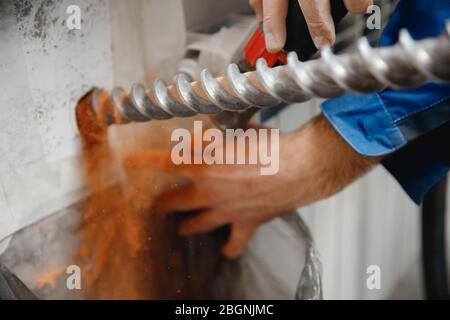 Baumeister Arbeiter Mann mit Hammer Bohrer Perforator Ausrüstung, die Loch in grauen Wand Konstruktion Stockfoto