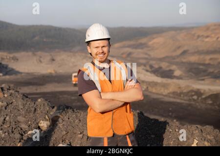 Ingenieur lächelnder Mann in weißem Helm auf Hintergrund Tagebau Mine Industrie Stockfoto