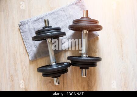 Zwei Hanteln liegen mit einem Handtuch auf dem Boden, Heimtraining Stockfoto