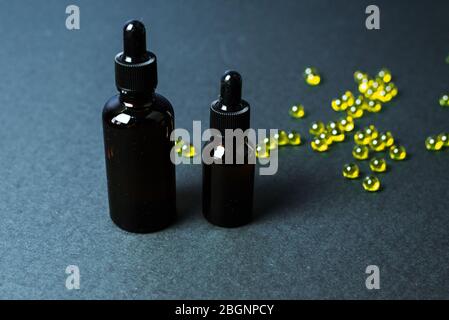 Feuchtigkeitsspendende und heilende Hautserum mit Vitamin C auf schwarzem Hintergrund. Vitaminkapseln als Ergänzung zu einer Creme oder Essenz für die häusliche Pflege. Stockfoto