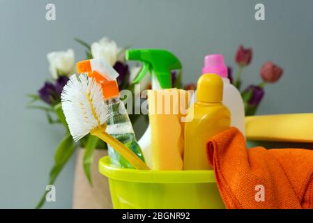 Waschmittel befinden sich in einem Eimer auf grauem Hintergrund. Reinigung in einem Haus. Haus reinigen und waschen. Stockfoto