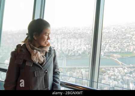 Eine Thailänderin in grauem Pullover und rosa Schal blickt vom Deck des Tokyo Skytree Turms auf die Stadt Tokio. Tokio, Japan, 7. Februar 2020 Stockfoto