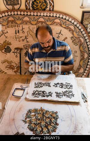 Jordan, Madaba, Handwerkszentrum Mosaic Workshop, MOSAIKIST im Handwerkszentrum Mosaic Workshop nutzt Zangen, um die Fliesenstücke für sein Mosaikstück in Arbeit zu Formen. Alle Mosaikisten, die im Zentrum arbeiten, sind rollstuhlgebunden und haben hier die Kunst der Mosaiken gelernt, um ihnen die Möglichkeit zu geben, ihren Lebensunterhalt zu verdienen. Stockfoto