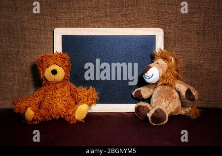 Zwei niedliche Teddybären sitzen neben der Tafel Stockfoto