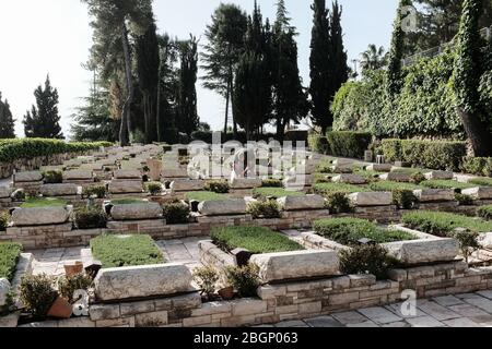 Jerusalem, Israel. April 2020. Ein Gärtner berührt die Gräber der Gefallenen am Mt. Herzl Militärfriedhof vor dem Memorial Day, der am 28. April 2020 begangen wird, da die Regierung am Memorial Day und am folgenden Independence Day eine landesweite totale Sperre ankündigt, wobei alle Zeremonien und Feiern abgesagt werden, um die Ausbreitung der COVID-19 weiter einzudämmen. Quelle: Nir Alon/Alamy Live News Stockfoto