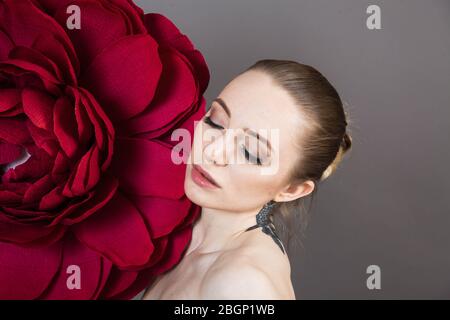 Schönes Mädchen mit gesunder Haut entspannt nach einer Spa-Behandlung mit einer roten Blume Stockfoto