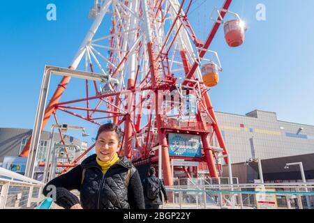 Eine Asain-Touristen-Dame fotografiert am Mori-Gebäude mit riesigen Riesenrädern dahinter. Tokio, Japan Februar 8,2020 Stockfoto