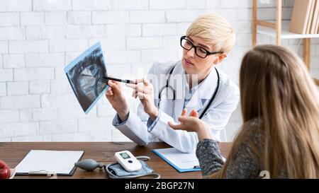 Ärztin im Büro, die dem Patienten Röntgenaufnahmen zeigt Stockfoto