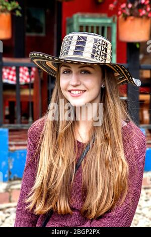 Ein junges hübsches Mädchen, das einen Sombrero vueltiao trägt (kolumbianisches Spanisch für gedrehten Hut), einen traditionellen kolumbianischen Hut, außerhalb einer traditionellen kolumbianischen 'Finca' Stockfoto