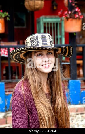 Ein junges hübsches Mädchen, das einen Sombrero vueltiao trägt (kolumbianisches Spanisch für gedrehten Hut), einen traditionellen kolumbianischen Hut, außerhalb einer traditionellen kolumbianischen 'Finca' Stockfoto