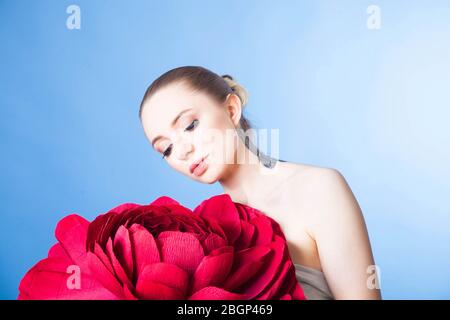 Schönes Mädchen mit gesunder Haut entspannt nach einer Spa-Behandlung mit einer roten Blume Stockfoto