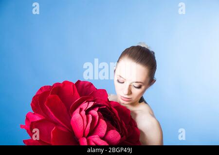 Schönes Mädchen mit gesunder Haut entspannt nach einer Spa-Behandlung mit einer roten Blume Stockfoto