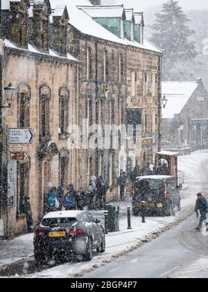 Die Schüler stehen im Schnee für einen Bus und warten auf einen Schneetag. Rothbury, Northumberland, Großbritannien. Stockfoto