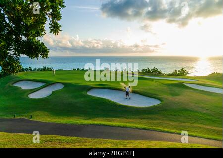 Männliche Touristen im Urlaub schlagen einen Golfball aus einer Sandfalle in der Nähe eines grünen, Port Royal Golfplatz Stockfoto