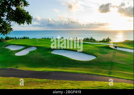 Männliche Touristen im Urlaub schlagen einen Golfball aus einer Sandfalle in der Nähe eines grünen, Port Royal Golfplatz Stockfoto