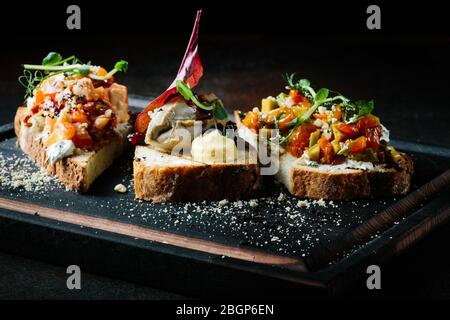 Köstliche italienische Bruschetta mit Tomaten, Fleischpastete, Oliven, Frischkäse. Ein Set mit leckeren Sandwiches für die Vorspeise. Stockfoto