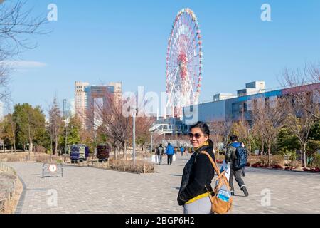 Eine Asain-Touristen-Dame fotografiert am Mori-Gebäude mit riesigen Riesenrädern dahinter. Tokio, Japan Februar 8,2020 Stockfoto