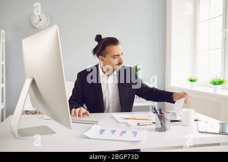 Geschäftsmann in einer schwarzen Jacke arbeitet online. Analysen am Computer im Büro. Stockfoto