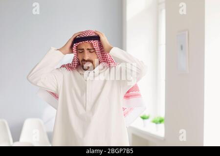 Arabischer männlicher Geschäftsmann hält seinen Kopf mit der Hand hat Stress Probleme Müdigkeit im Büro Stockfoto