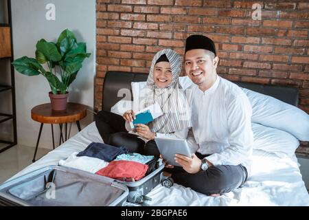 Glückliches Porträt von jungen muslimischen Paar mit Pass und Tablet-Verpackung für den Urlaub Stockfoto