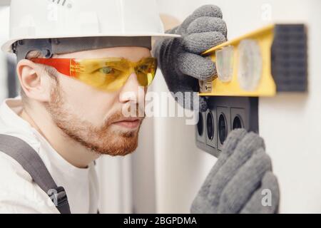 Elektriker installieren Schalter und Steckdosen prüft Werkzeug Ebenheit zu Hause Stockfoto