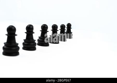 Sechs schwarze Schachfiguren, die in einer Linie vor einem isolierten weißen Hintergrund platziert sind Stockfoto