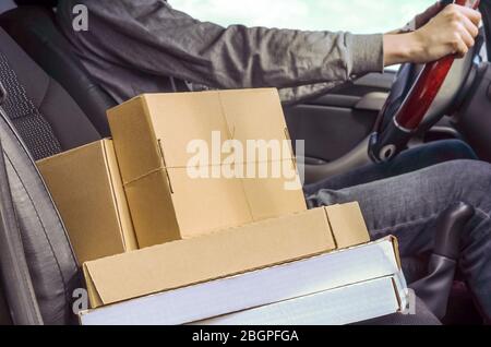 Kurier mit Paketen im Auto. Lieferung von Paketen, Waren, Pizza. Lieferer. Sichere Lieferung während der Quarantäne des Coronavirus. Stockfoto