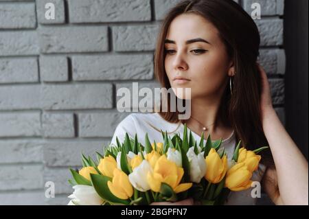 Mädchen mit dunklen Haaren, die den Strauß Tulpen in der Hand halten Stockfoto