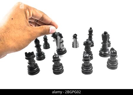 Schwarze Schachfiguren auf einem weißen isolierten Hintergrund platziert, während eine Person sie sortiert Stockfoto