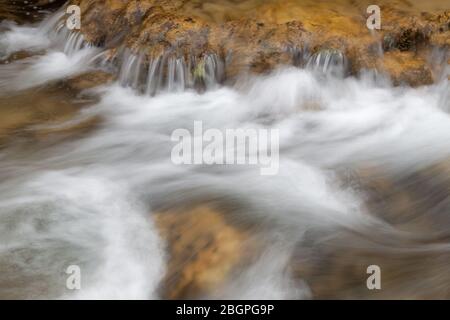 Wunderschöne Nahaufnahme Details und Formen von mächtigen Bergbach Stromschnellen Kaskaden über rote, nasse Felsen eines Canyons Stockfoto