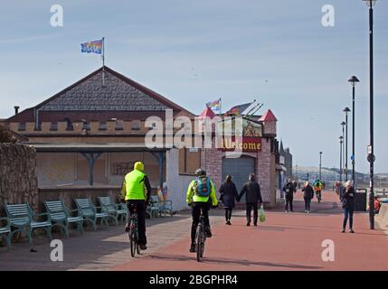 Portobello, Edinburgh, Schottland, Großbritannien. April 2020. Sehr ruhige Promenade und Strand, Temperatur 11 Grad mit Wind ENE 15mph, mögliche Böen von 23 mph, wie die NHS danke Flagge zeigt. Fußgänger mischten sich mit Radfahrern auf der Promenade oft zu eng für richtige körperliche soziale Distanz und wenige Menschen am Sandstrand. Quelle: Arch White/Alamy Live News. Stockfoto