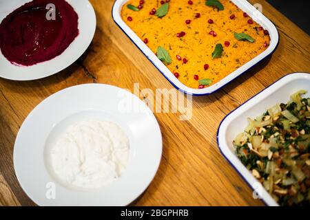 Eine Auswahl an gesunden, nahrhaften veganen Gerichten, die bereit sind, an einem Esstisch serviert zu werden Stockfoto