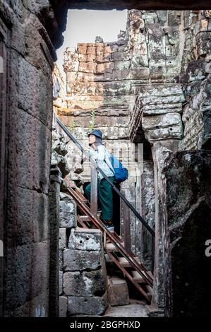 Asiatische Touristen machen ihren Weg durch die alten Tempel von Angkor Wat, Kambodscha. Selfies machen, Leitern klettern, durch die Gänge gehen und nehmen Stockfoto