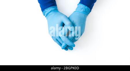 Blaues Banner mit Nitrilhandschuhen. Hände eines Sanitäter in den blauen Latexhandschuhen auf weißem Tisch Stockfoto