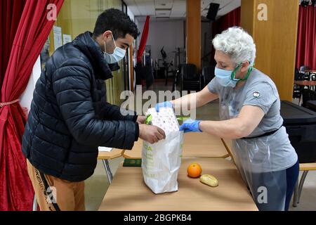 Ein Freiwilliger aus dem Rathaus von El Vendrell, der eine chirurgische Maske und Schutzhandschuhe trägt, liefert eine Person, die nach der Schließung von sozialen Esszimmern aufgrund der Pandemie von Covid-19 Sozialdienst leistet, Lebensmittel an eine Person, die Sozialhilfe erhalten hat. Das Ministerium für Sozialdienste des Stadtrats von El Vendrell (Tarragona Spanien) Verteilt rund 70 Personen an Lebensmitteln, die an Menschen der sozialen Hilfe vergeben werden. Die Santa Teresa Private Foundation und die Freiwilligen der School of Hospitality von Santa María del Mar von El Vendrell bereiten die Catering-Art von Menüs und das Essen aufgrund der Sicherheitsmaßnahmen der Covid-19 Pandemie. Stockfoto