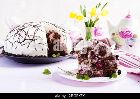 Schokoladenkuchen mit Kirschen und Sahne auf hellem Hintergrund. Stockfoto