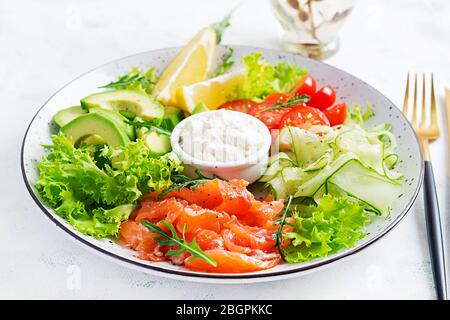 Salat aus gesalzenem Fisch, Lachs, Avocado, Kirschtomaten, Gurke, Salat und Frischkäse. Fischmenü. Diätmenü. Meeresfrüchte - Lachs. Stockfoto