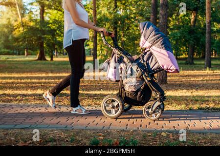 Muttertag. Junge Frau zu Fuß im Frühlingspark mit Babywagen. Mutter verbringt Zeit mit ihrem Kind im Freien Stockfoto