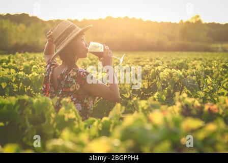 Asiatische Frau, die Rotwein im Weinberg während ihres Urlaubs trinkt, Vintage-Stil Stockfoto